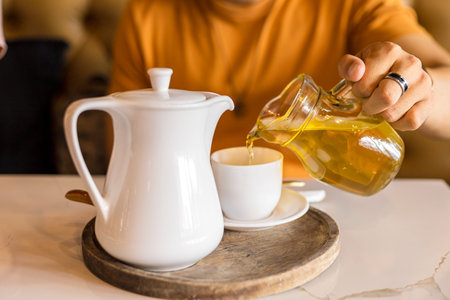 Hand pour tea in to cup of tea on the table.