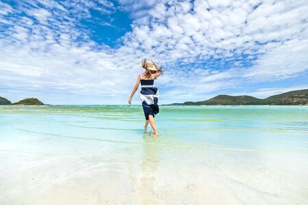 Happy Woman in summer vacation wearing hat and dress enjoying the view at the island beach.の写真素材