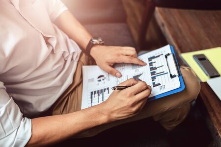 Businessman hold pen and working calculate data. document graph chart and report marketing. Business office concept.の写真素材