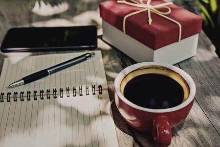 Coffee cup on the table near paper short note and gift box.の写真素材