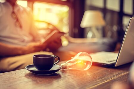 light bulb on the table near cup of coffee and laptop. idea, Business conceptの写真素材