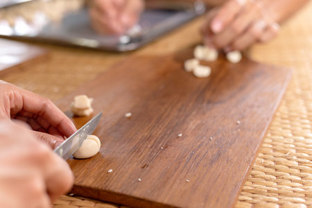 Woman cuts dough for baking knife, dough lying on wood board.