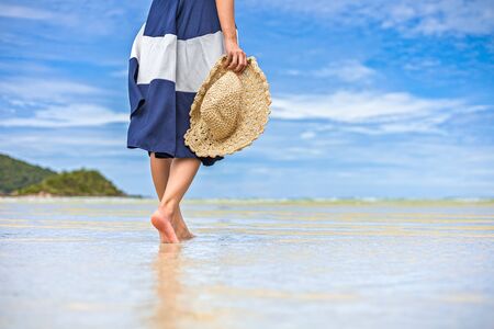 Happy Woman in summer vacation hold hat and wearing dress enjoying the view at the island beach.の写真素材