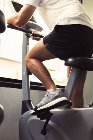 Fit man working out on exercise bike at the gym. Healthy and funny lifestyle concept.の写真素材