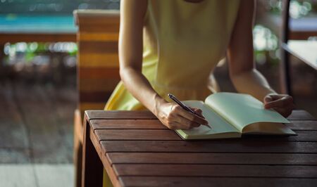 Hand hold pen and writing a book on the table.の写真素材