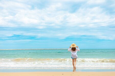 Happy Woman in summer vacation wearing hat and dress enjoying the view at the island beach.の写真素材