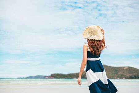 Happy Woman in summer vacation wearing hat and dress enjoying the view at the island beach.の写真素材