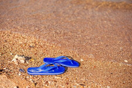 Pair of flip flops on the beach and water flow.の写真素材