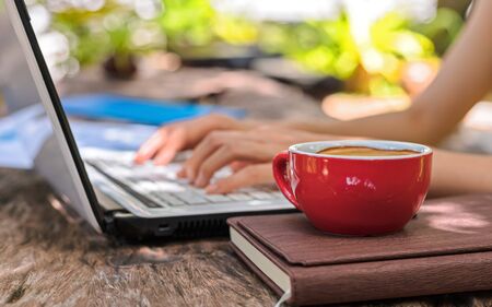 Cup of coffee on the book near business women working on laptop.の写真素材