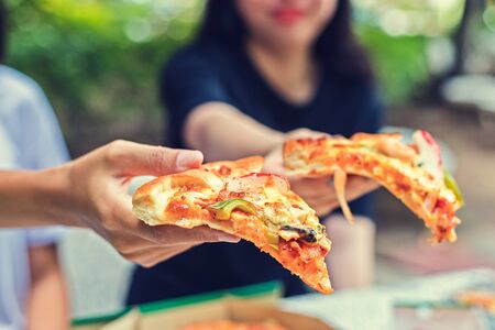 office people group taking and sharing pizza slices from box on table. Employees team workers eating together enjoy at work break, delivery service concept.の写真素材
