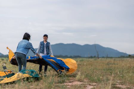 People Pitch a tent on the ground near the lake. Relaxing, traveling, long weekend, holiday concept.の写真素材