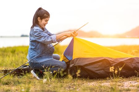 People Pitch a tent on the ground near the lake. Relaxing, traveling, long weekend, holiday concept.の写真素材