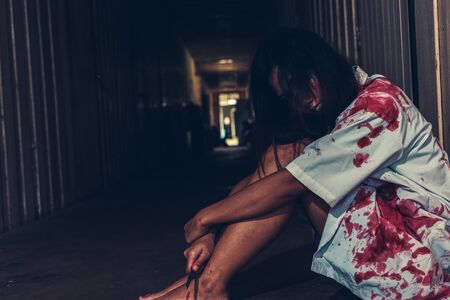 horror scence of women hold knife by hands with blood. Ghost women wear white dress stain blood at abandoned house
. Halloween conceptの写真素材