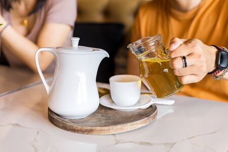 Hand pour tea in to cup of tea on the table.の写真素材