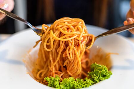 Spaghetti on a fork. Girl use fork with spaghetti. Pasta with red sauce.の写真素材