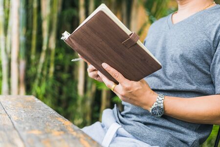 A man hold book and reading in the parks near the river.の写真素材