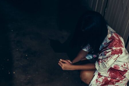 horror scence of women hold knife by hands with blood. Ghost women wear white dress stain blood at abandoned house
. Halloween conceptの写真素材