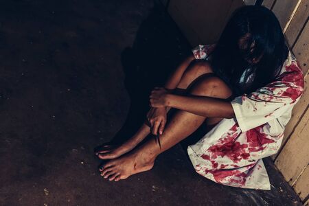 horror scence of women hold knife by hands with blood. Ghost women wear white dress stain blood at abandoned house
. Halloween conceptの写真素材