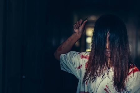 horror scence of women hold knife by hands with blood. Ghost women wear white dress stain blood at abandoned house
. Halloween conceptの写真素材