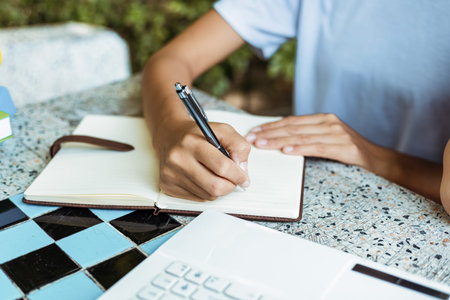 close up of woman's hands hold pen and writing in notepad
