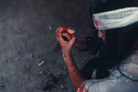 horror scence of women hold knife by hands with blood. Ghost women wear white dress stain blood at abandoned house
. Halloween conceptの写真素材