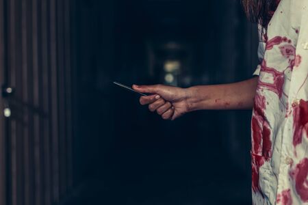 horror scence of women hold knife by hands with blood. Ghost women wear white dress stain blood at abandoned house
. Halloween conceptの写真素材