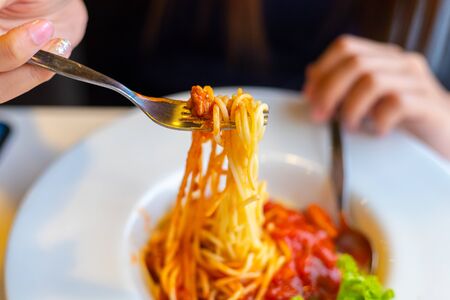 Spaghetti on a fork. Girl use fork with spaghetti. Pasta with red sauce.の写真素材