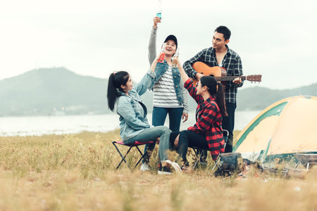 Group of Friends  having fun together and drinking at camping near the lake and mountian back.