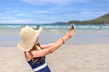 Women ware hat take a shot by herself on the beach in summer travel.の写真素材