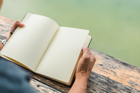A man hold book and reading in the parks near the river.の写真素材