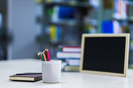 crayon in pencil case near book and black board on the table.の写真素材