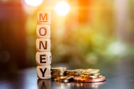 wood cube word "money" near gold coin on the table.の写真素材