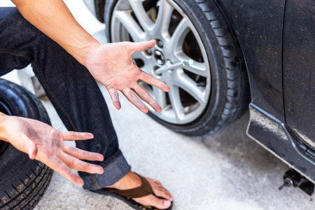 Man show hands of dirty after change a flat car tire at car park with Tire maintenance, damaged car...