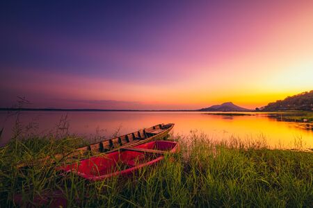 Old fishing boat in the water at resorvoir between sunset.の写真素材
