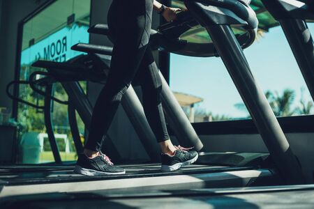 foot Fitness girl running on track treadmill, exercise, workout at fitness gym.の写真素材