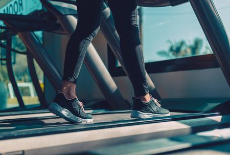 foot Fitness girl running on track treadmill, exercise, workout at fitness gym.の写真素材