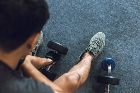 A man lifting dumbbells on the ground in a gym. Sport man at fitness.の写真素材