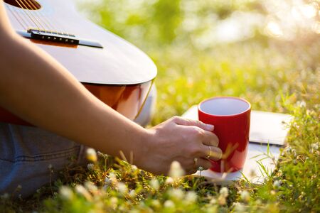 Women hold cup of coffee and coffee on a book in the park;の写真素材
