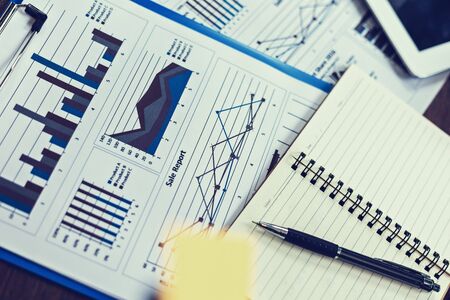 Glasses, book, paper graph and tablet on the table. Object of business concept.の写真素材
