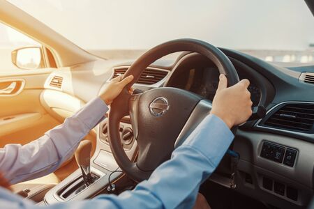 Business women drive car on the road in the city. Hands control car steering wheelの写真素材