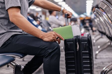 people sitting and waiting for check in at airport. A man and luggage at the airport terminal.の写真素材