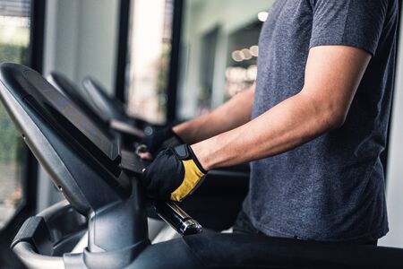 A man running on the running  machine in gym. Sport and exercise concept.