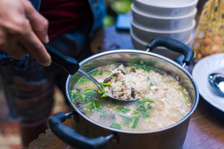 A man scooping rice soup.