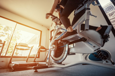 Exercise bike cardio workout at fitness gym. women doing sport biking in the gym for fitness.