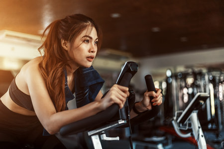 Exercise bike cardio workout at fitness gym. women doing sport biking in the gym for fitness.