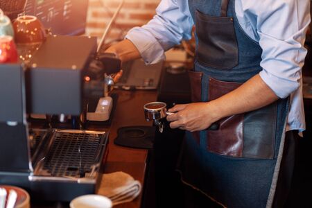 Barista holding portafilter and coffee tamper making  coffee at cafe.の写真素材