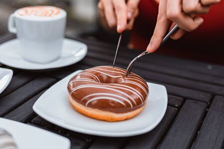 Close up of hands with fork and knife cutting donut shape.
の写真素材