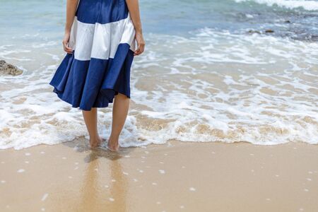 Woman barefoot walking on summer along wave of sea water and sand on the beach. の写真素材