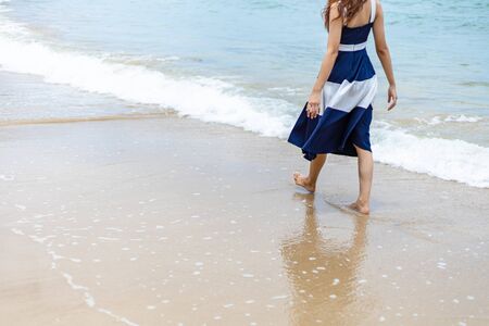Woman barefoot walking on summer along wave of sea water and sand on the beach. の写真素材