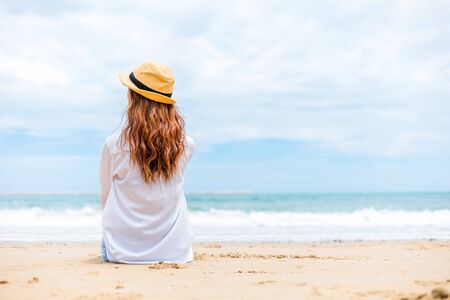 Portrait pretty woman and hat sitting on the beachの写真素材